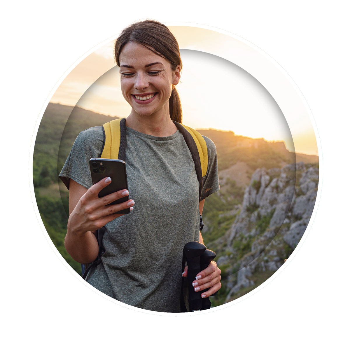 A woman smiles brightly as she looks at her cellphone, appearing pleased and excited by what she sees.