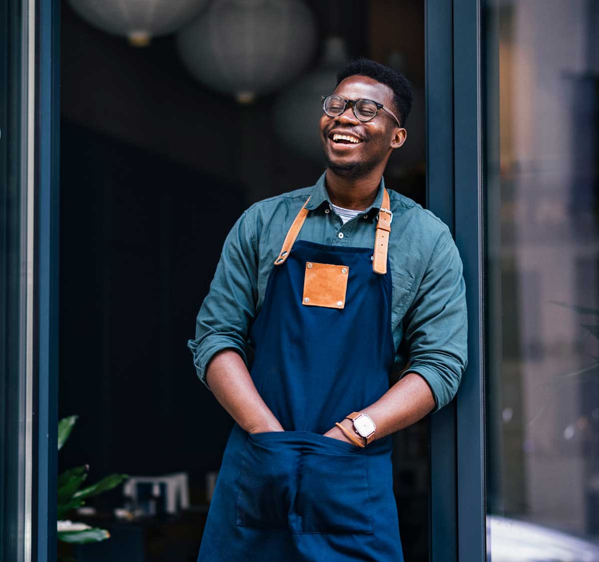 Man wearing apron stands in front of business